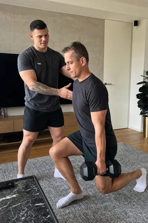 Individuelles Personal Training fuer Einsteiger zu Hause Tim Haaf korrigiert die Haltung eines Mannes um die 45 beim Krafttraining zu Hause
